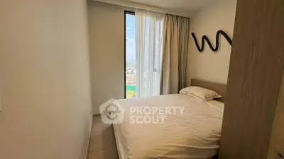 Cozy bedroom with large window offering stunning city view, modern decor and ample natural light.