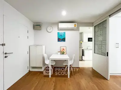 Modern dining area with wooden flooring and compact kitchen in open layout apartment