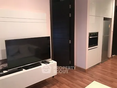 Modern living room with sleek TV setup and integrated kitchen appliances.