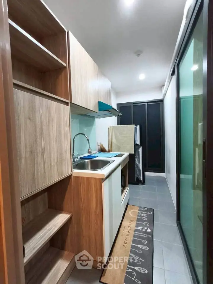 Modern compact kitchen with sleek cabinetry and sliding glass doors in a stylish apartment.