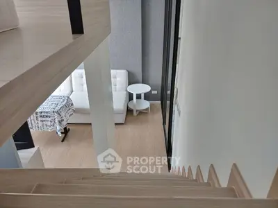Modern loft-style living room with wooden staircase and cozy seating area.