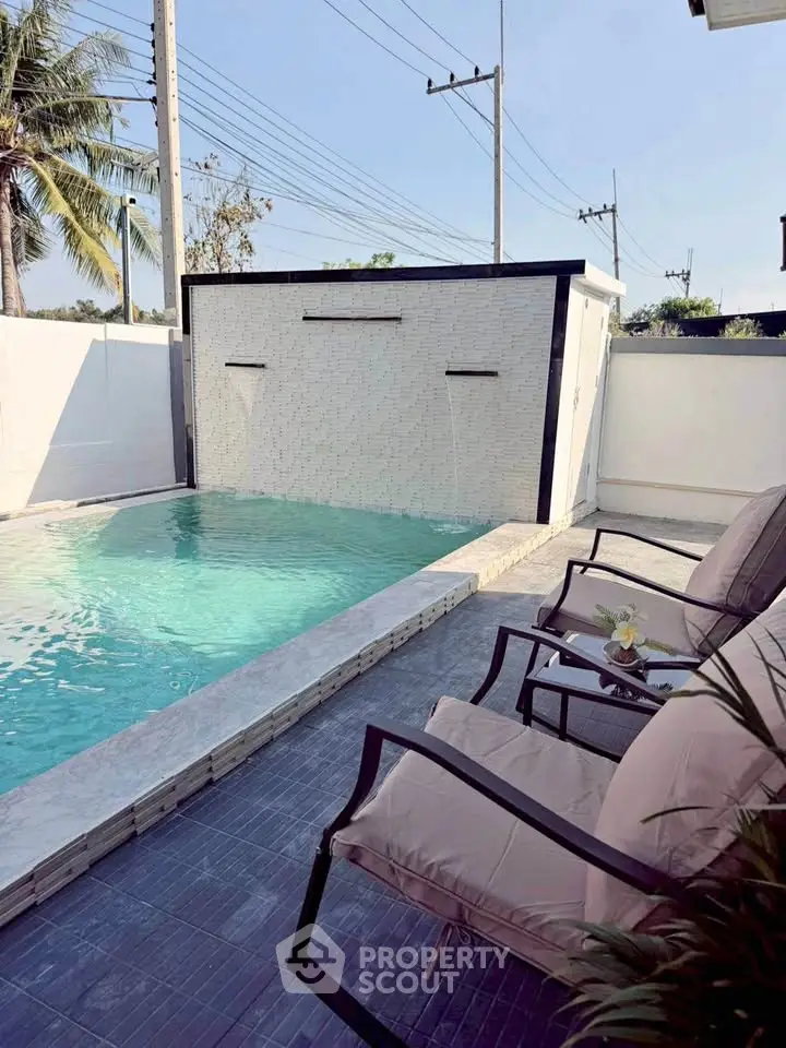 Luxurious private pool with modern waterfall feature and cozy seating area.