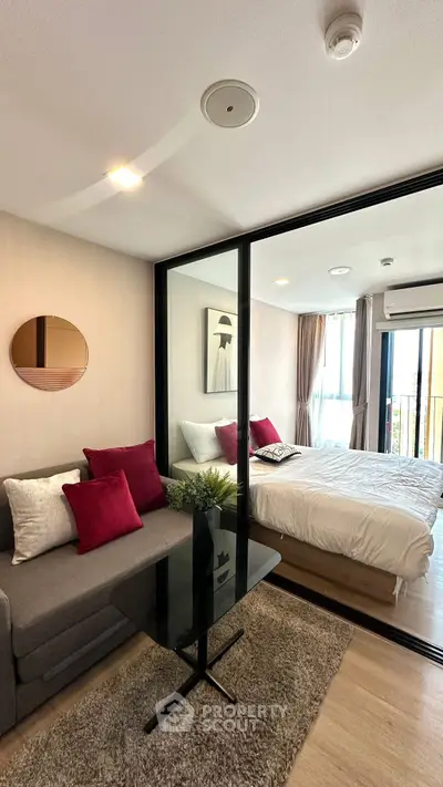 Modern studio apartment with glass partition, cozy living area, and stylish bedroom.