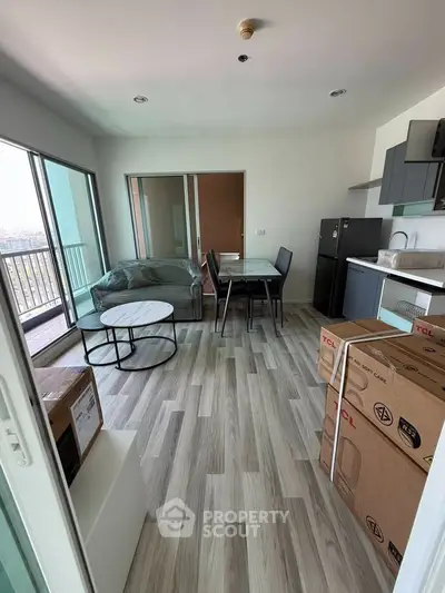 Modern living room with open kitchen and balcony view, featuring sleek furniture and stylish flooring.