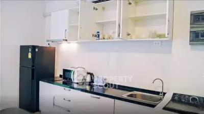 Modern kitchen with sleek black countertop, built-in appliances, and ample storage space.