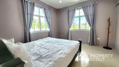 Spacious bedroom with large windows and elegant curtains, offering ample natural light and serene ambiance.