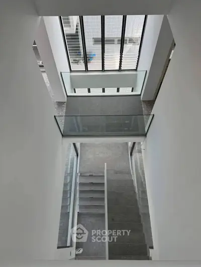 Modern staircase with glass railing and large windows in contemporary building