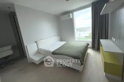 Modern bedroom with large window and minimalist design in a high-rise apartment.