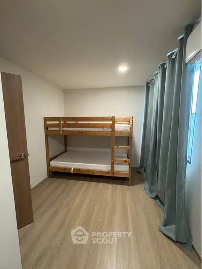 Cozy bedroom with wooden bunk bed and modern decor, perfect for small spaces.