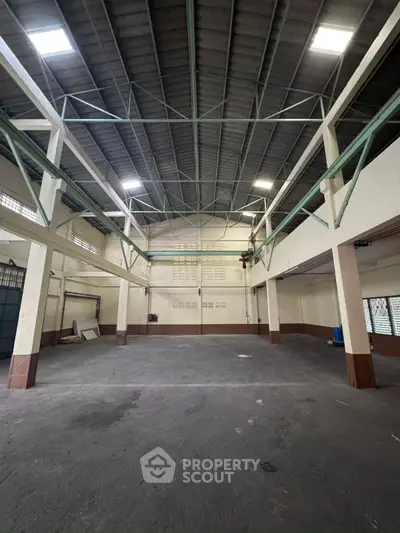 Spacious industrial warehouse with high ceilings and ample natural light, perfect for storage or manufacturing.