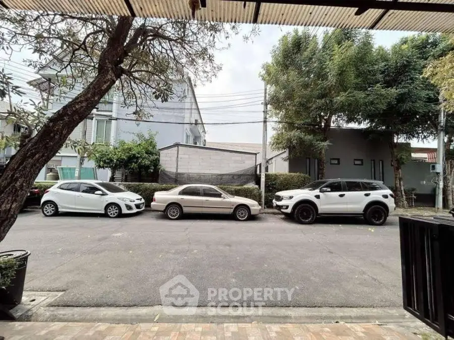 Street view with parked cars in front of modern residential buildings.