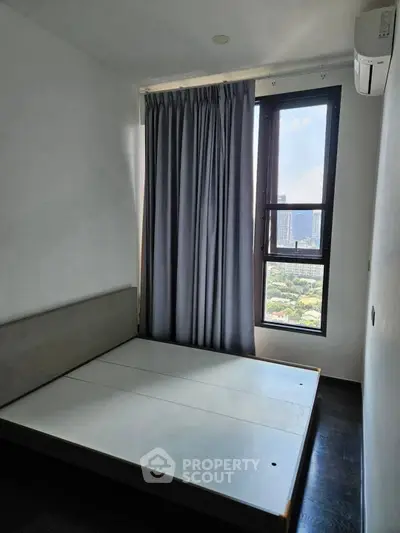 Modern bedroom with large window offering stunning city view and natural light.