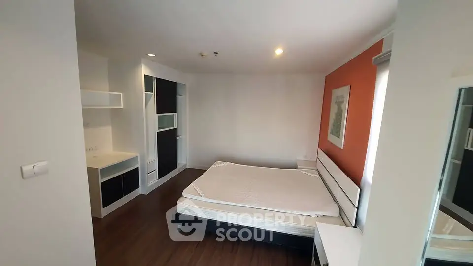 Spacious bedroom with modern furnishings and hardwood flooring in a stylish apartment.