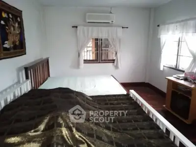 Cozy bedroom with double bed, air conditioning, and natural light from two windows.