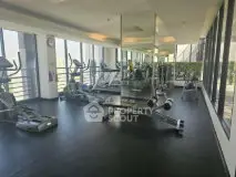 Spacious gym with modern equipment and large windows offering natural light.