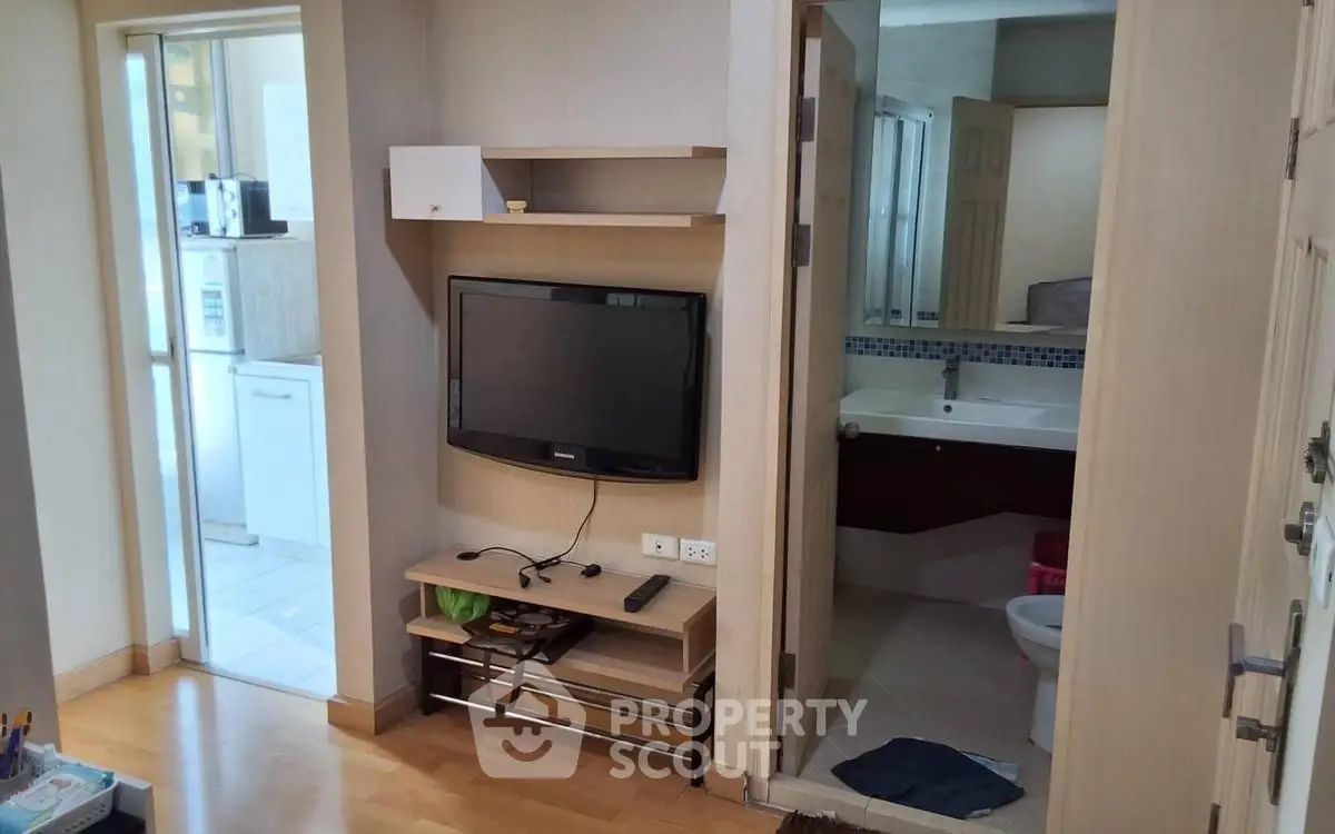 Compact apartment interior with TV, bathroom, and kitchen view