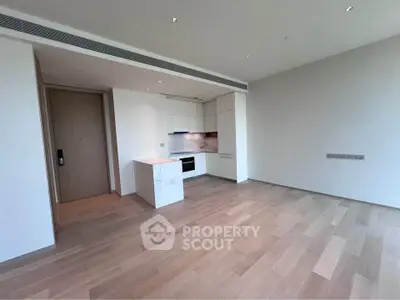 Modern open-plan kitchen with sleek design and wooden flooring in a spacious apartment.