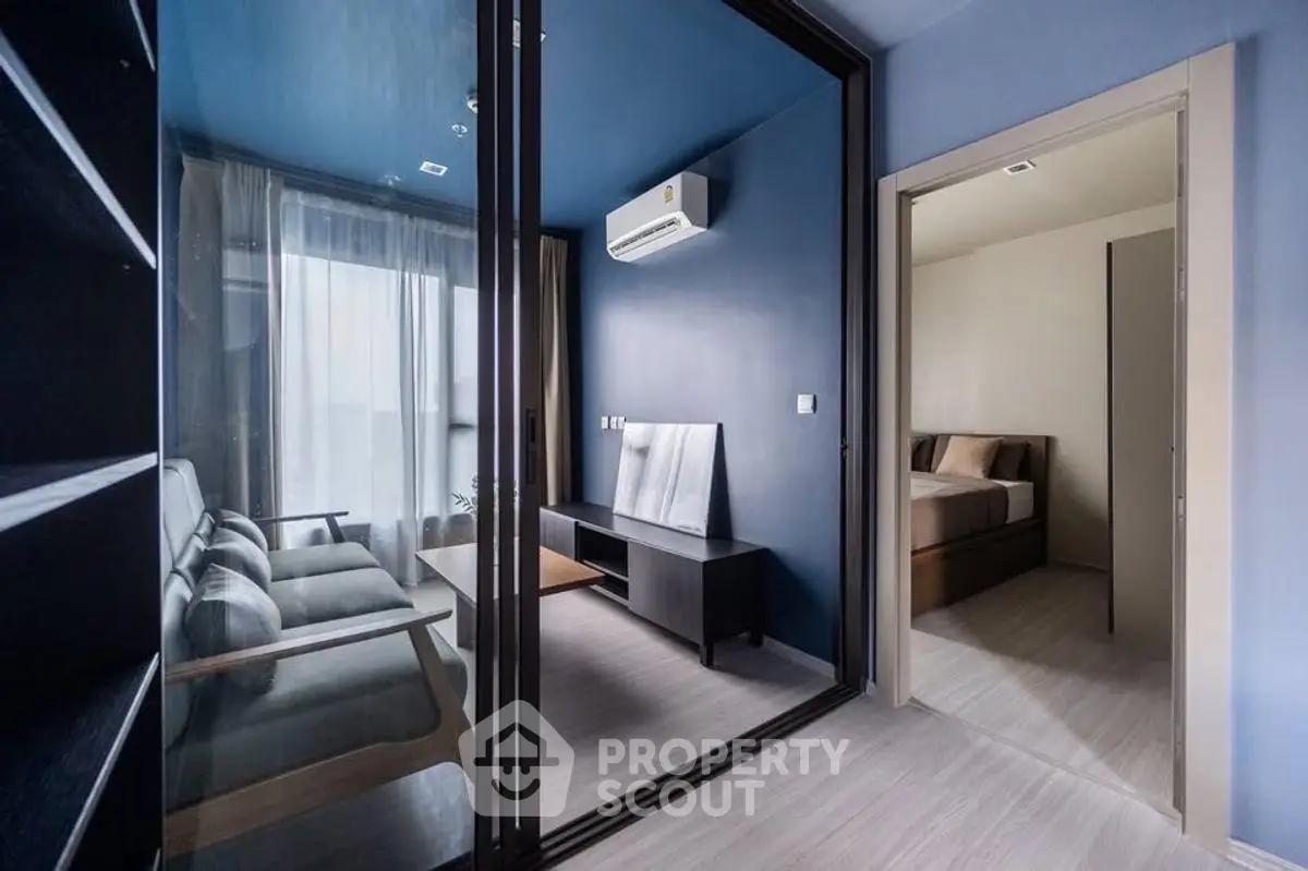 Modern apartment interior with glass partition, cozy living area, and adjacent bedroom.
