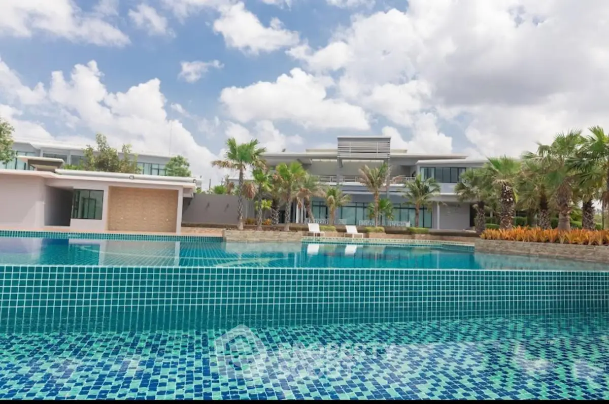 Luxurious modern villa with stunning pool and lush landscaping under a bright blue sky.