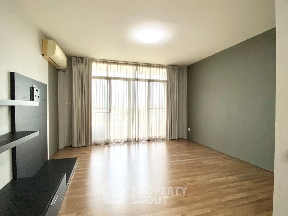 Spacious empty living room with large window and wooden flooring