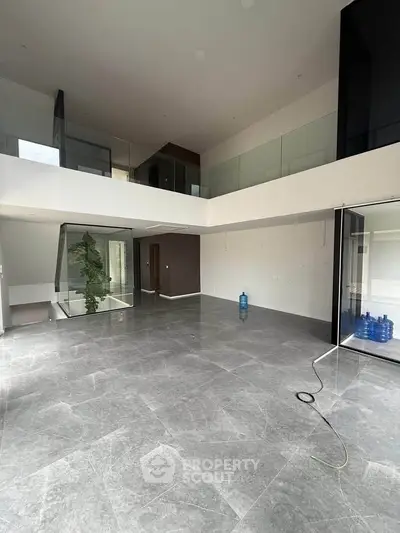 Spacious modern interior with high ceilings and large windows, featuring sleek marble flooring.