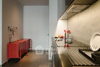 Modern kitchen with sleek countertops and stylish red accents, perfect for culinary enthusiasts.