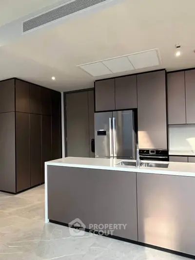 Modern kitchen with sleek cabinetry and stainless steel appliances in luxury apartment.