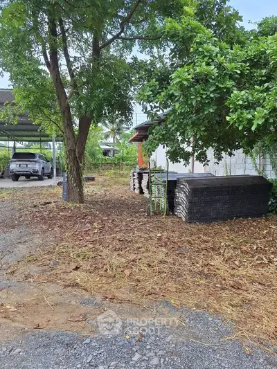 Spacious outdoor area with trees and construction materials, ideal for development.