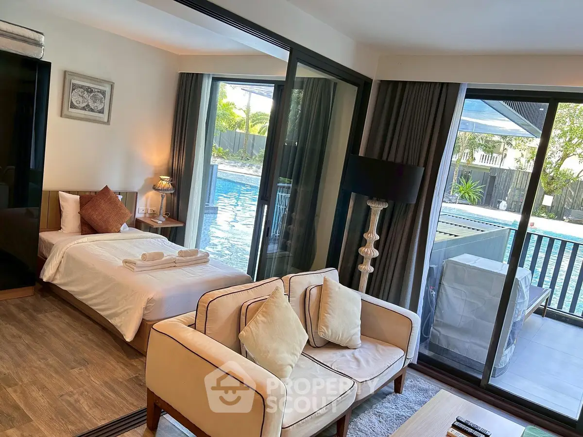 Luxurious open-plan living room with poolside view, elegant decor, and cozy seating area in modern apartment.