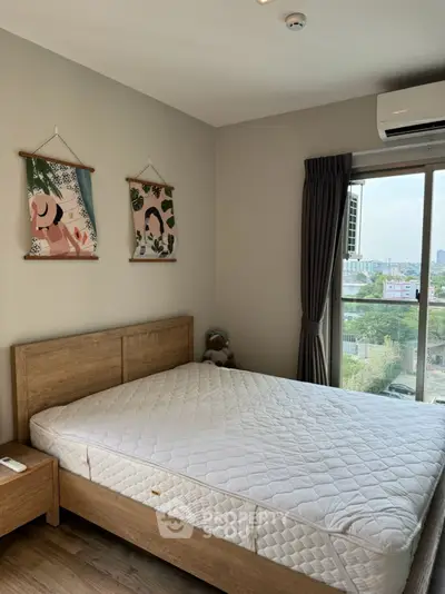 Cozy bedroom with large window offering city view, featuring wooden bed and modern decor.