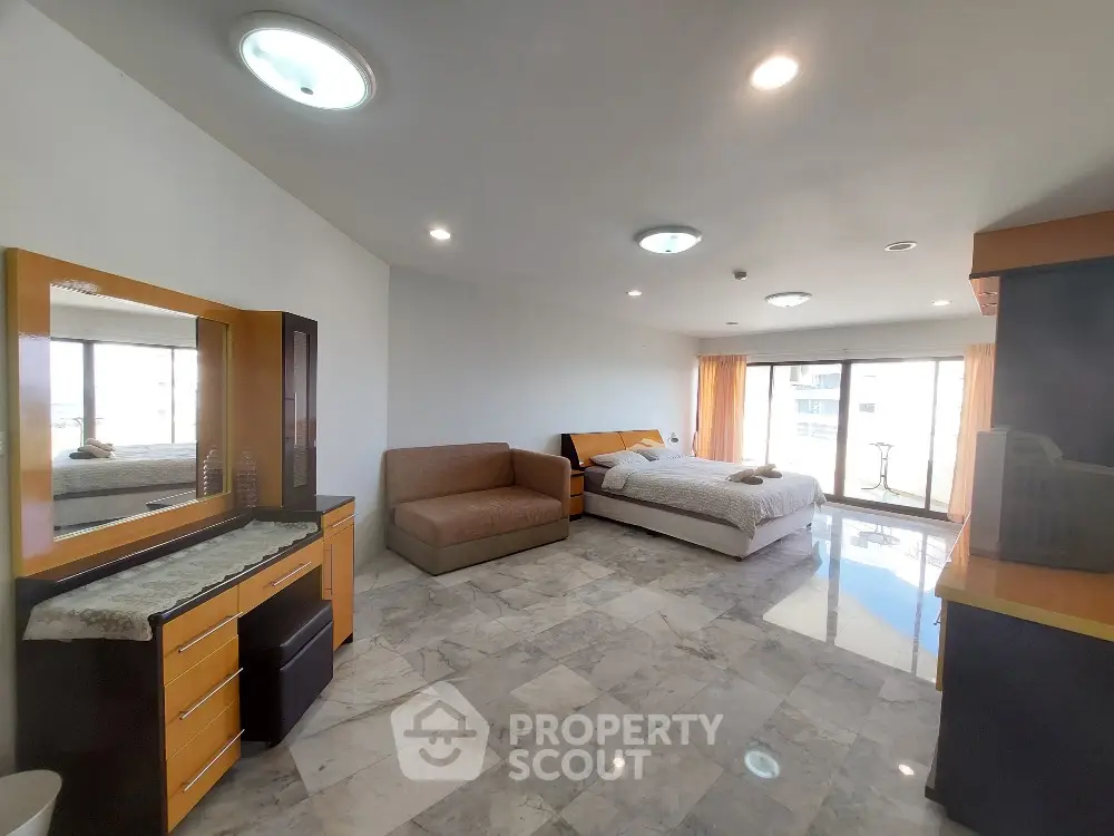 Spacious bedroom with modern furnishings and large windows offering natural light.