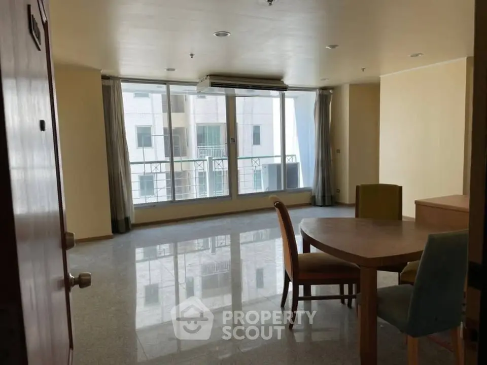 Spacious living room with large windows and dining area in modern apartment