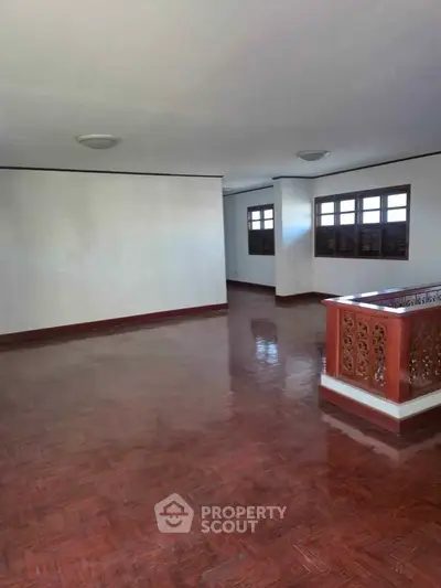 Spacious living area with polished wooden floors and elegant railing