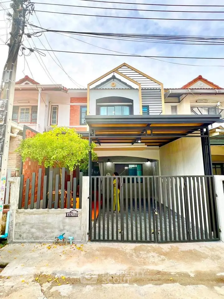 Charming two-story townhouse with modern facade and gated parking area.