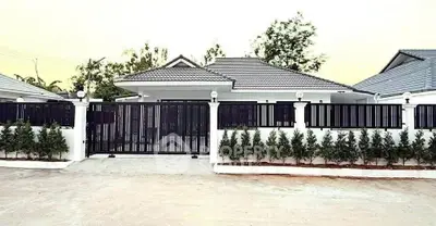 Charming single-story house with modern black fence and lush greenery, perfect for family living.