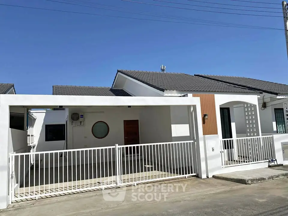 Modern single-story house with gated driveway and sleek design in a suburban neighborhood.