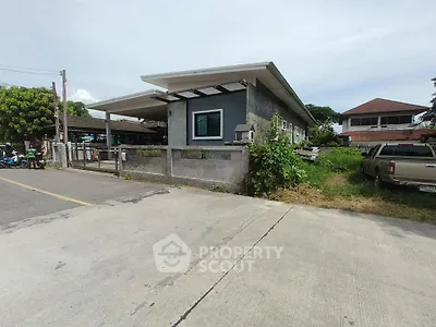 Modern single-story house with spacious driveway and lush greenery in suburban neighborhood.