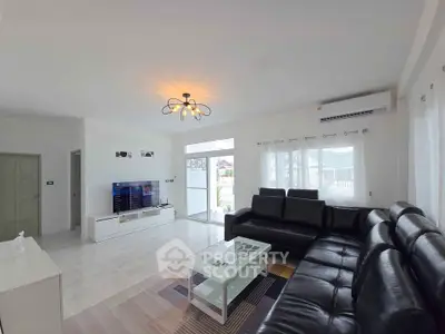 Spacious modern living room with sleek black leather sofa and large TV, perfect for relaxation.