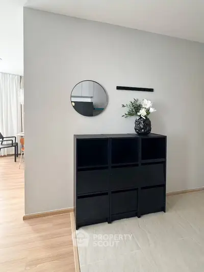 Modern interior with stylish black shelving and decorative mirror in a bright living space.