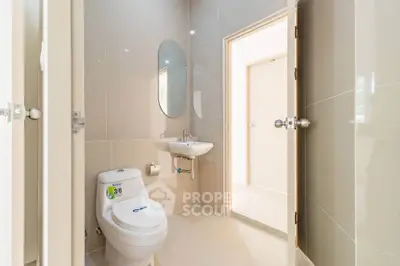 Modern bathroom with sleek fixtures and neutral tiles, featuring a compact design for efficient space use.