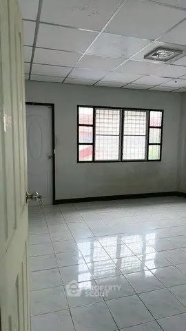 Spacious empty room with tiled floor and large windows, perfect for customization.