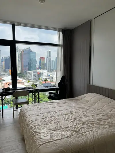 Modern bedroom with city view and large window, featuring a cozy bed and study desk.