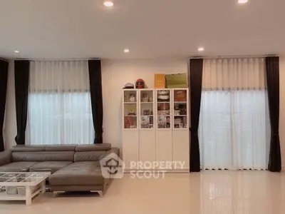 Spacious modern living room with sleek leather sofa and elegant display cabinet.