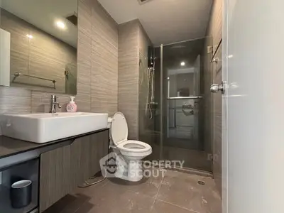 Modern bathroom with glass shower and sleek fixtures in contemporary apartment.