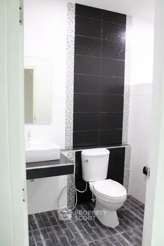 Modern bathroom with sleek black and white tile design and contemporary fixtures.