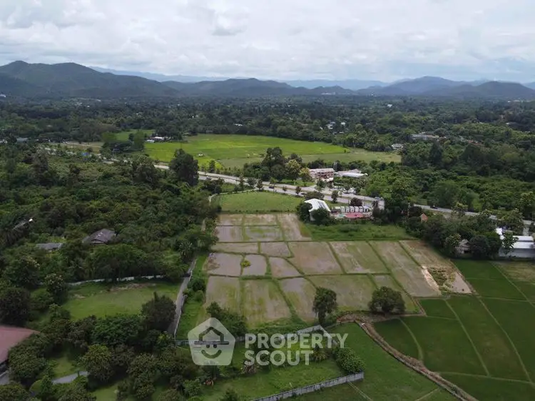 Scenic aerial view of lush green landscape with mountains in the background, ideal for real estate development.
