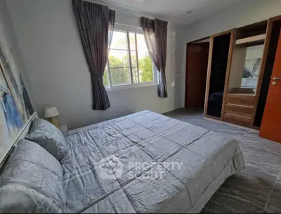 Spacious bedroom with large window and modern decor in a stylish home.