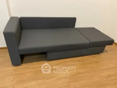 Modern gray sofa bed on wooden floor in minimalist living room.