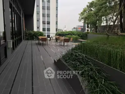 Spacious modern balcony with lush greenery and outdoor seating in urban setting.