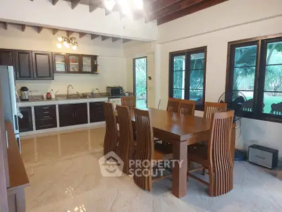 Spacious kitchen with wooden dining set and modern appliances in a bright, airy setting.